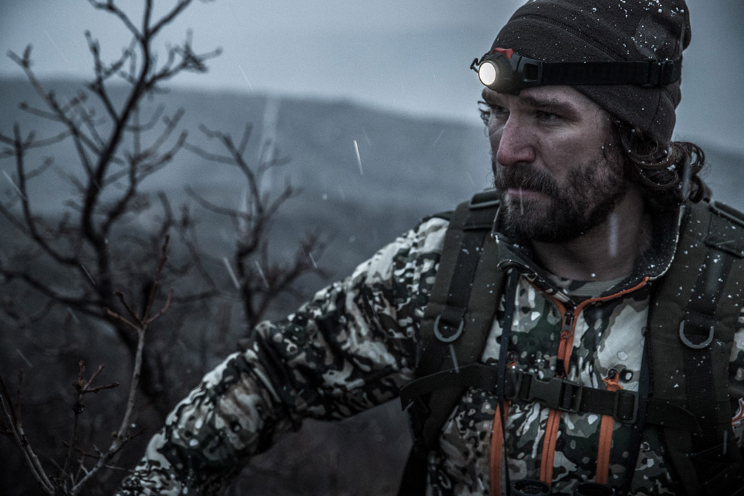 High above tree line, a hunter searches for game as a storm moves in.