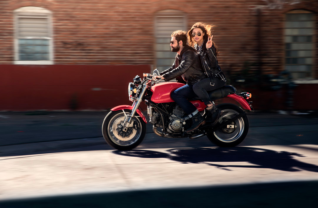 Woman and man riding ducati in the urban streets of Denver for fashion shoot.