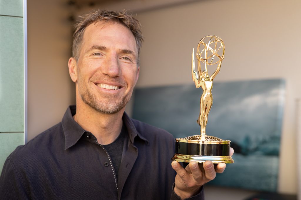 Tyler smiling and holding the Emmy Award he won for directing a Turning Point documentary.