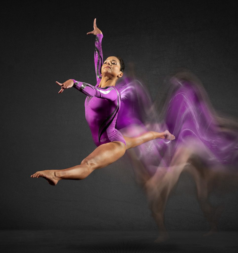 Olympic gymnast Jessica Lopez leaps with motion blur behind her.