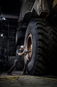 This Photograph Shows a Mine Worker Repairing One of the World's Largest Dumptruck. American Industry is Displayed in this Stark Image.