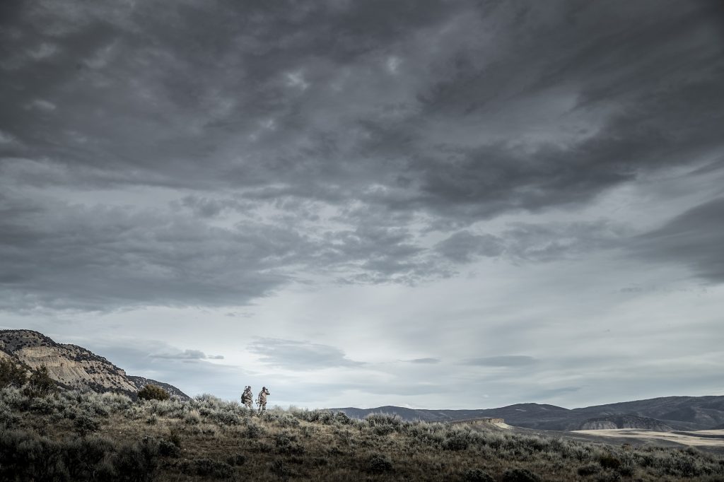 In the Vast Expanse of Sage Brush and Grasses, Two Hunters Search for their Quarry in this Stark Photograph.