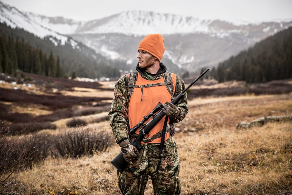 Rifle in Hand, this Big Game Hunter Poses in Front of Snow-capped Mountains. Portraits like this One Highlight the Rugged Nature of Hunting.