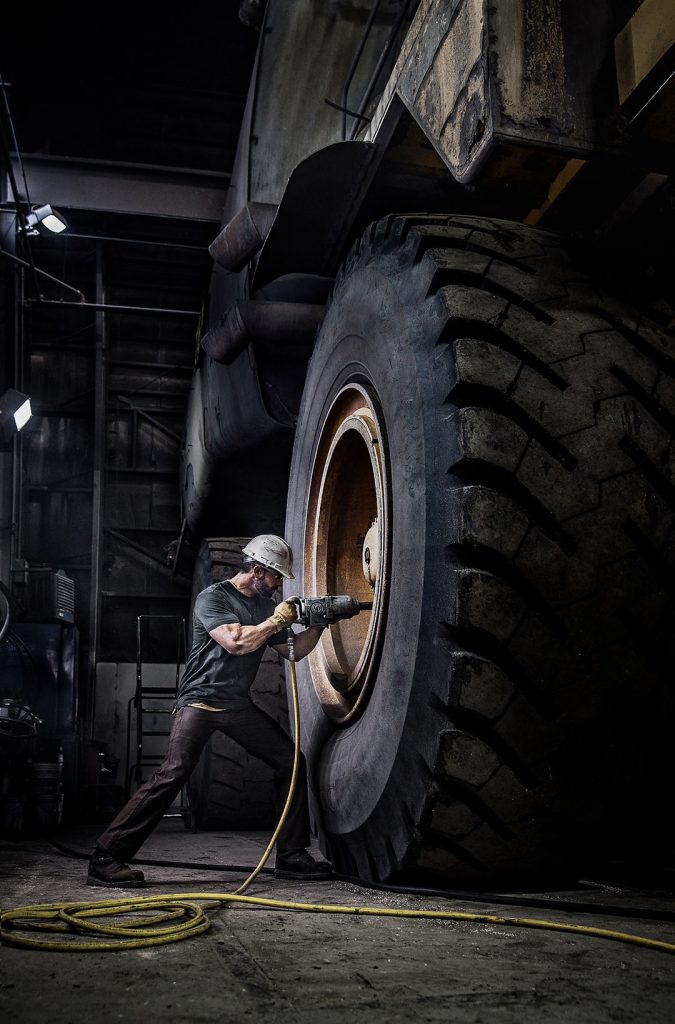 This Photograph Shows a Mine Worker Repairing One of the World's Largest Dumptruck. American Industry is Displayed in this Stark Image.