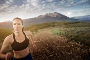 This photo of a Female Long-Distance Runner Shows Rugged Terrain of the Rocky Mountians in the Backdrop. Exercising in the Outdoors is Part of the Colorado Lifestyle.