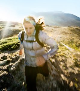 Action Shot of a Female Athlete Trail Running the Rocky Mountains. Award Winning Adventure Photographer Captures this Moment of Active Lifestyle.