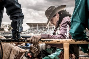 This Professional Cowboy Holds on the Railing in the Pen, Waiting for his Turn on a Bucking Bronco, His Eyes are Focused and Intent.