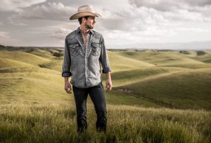 This Cowboy Pic, Taken in a Wide Open Ranchland, Highlights the Jeans, Cowboy Hat, Boots and Denim Shirt of this Unique Lifestyle.