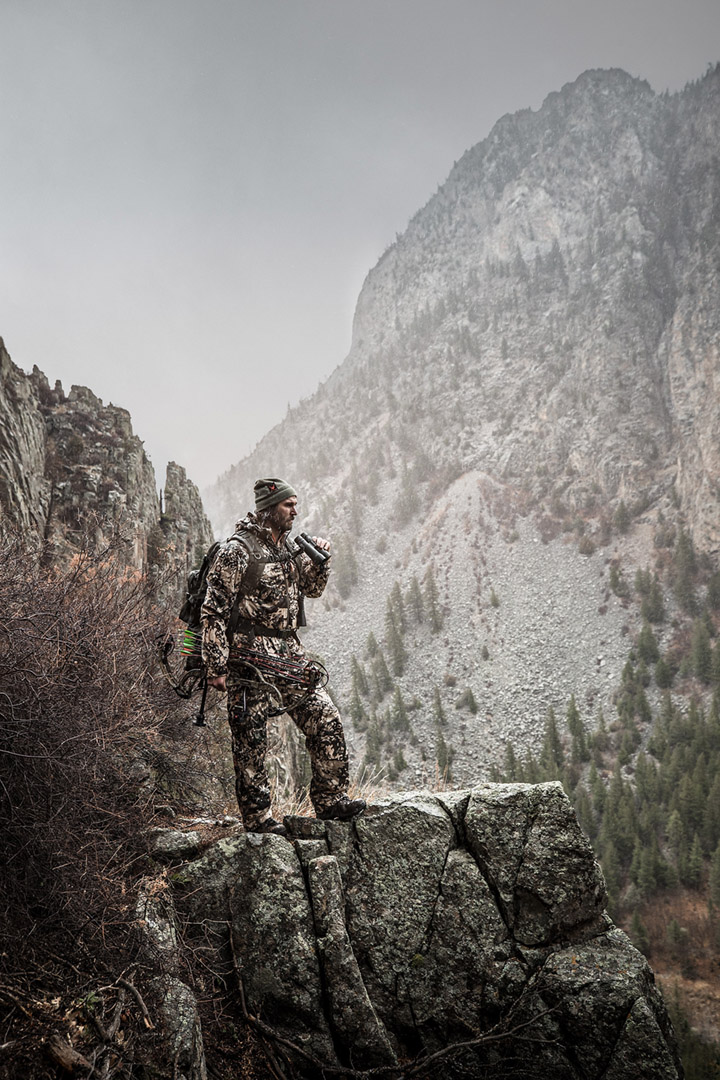 glassing the valley floor, a big game elk hunter in the alpine wilderness