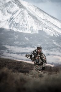 high above tree line, a hunter scans the brush for big game during bow hunting season.