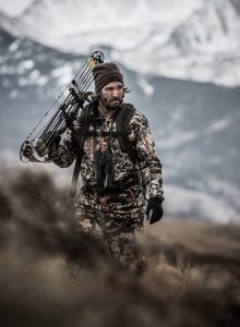 high above tree line, a hunter scans the brush for big game during bow hunting season.