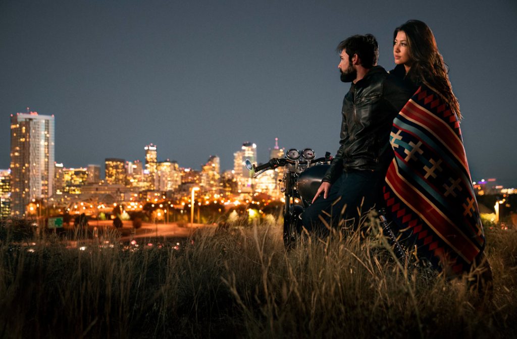 Couple at dusk on motorcycle overlooking the city of Denver.