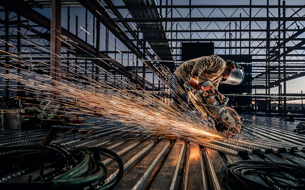 A steel worker sends sparks flying as he works in a steel yard.