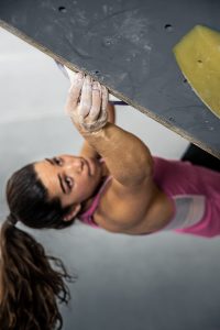 Brooke Raboutou reaches up and grabs a hold on a bouldering wall at Mesa Rim Climbing Academy.