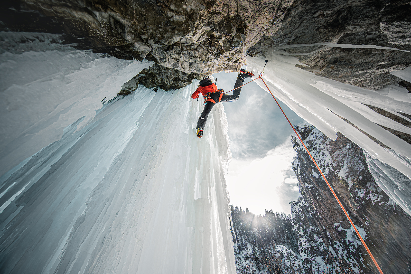 Climber Anna Pfaff stretches to reach her next step while ice climbing.